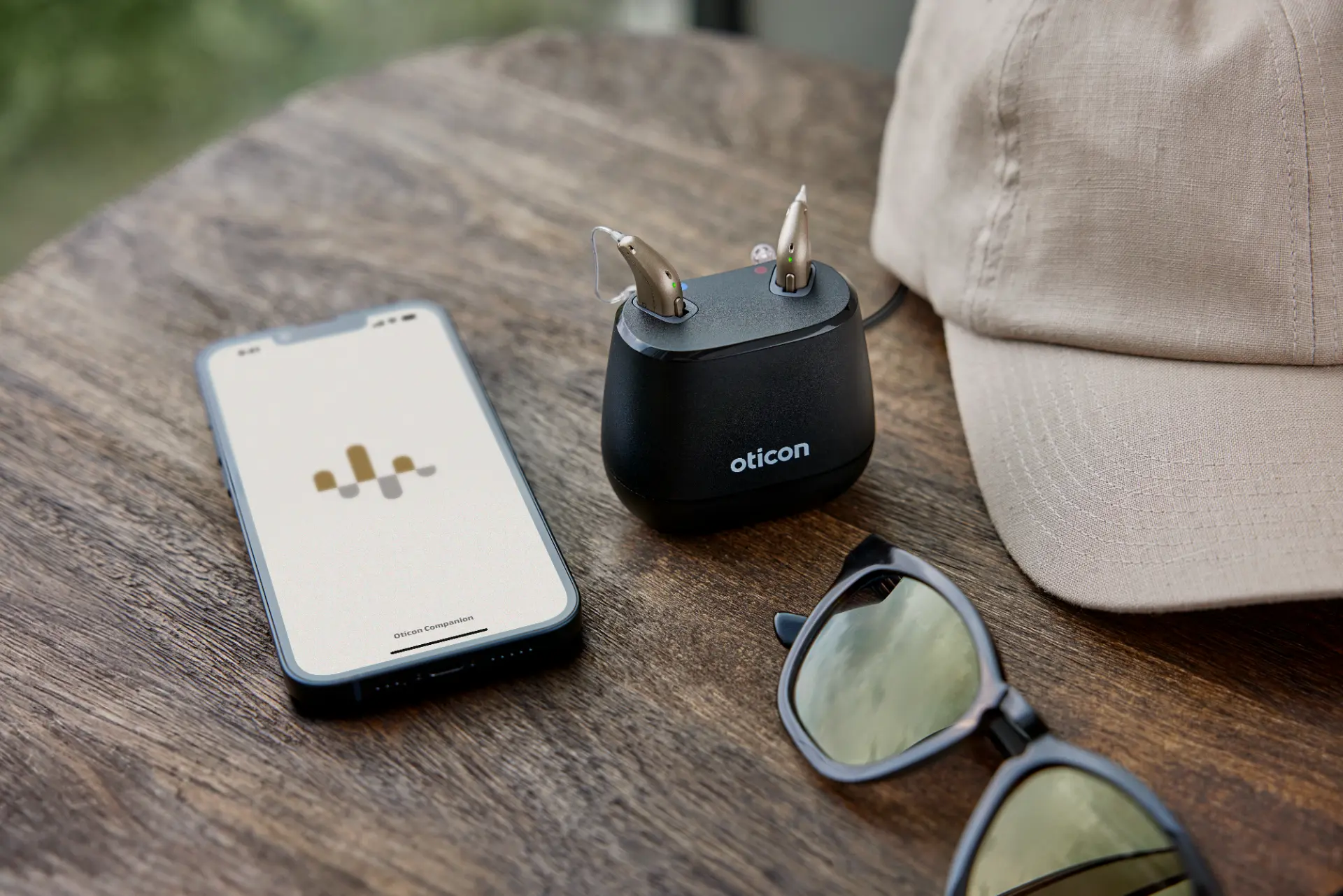 Oticon Intent høreapparater i ladestation ved siden af telefon med Oticon Companion-app